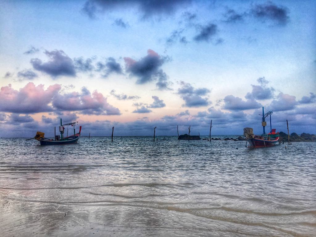sunset over samui thailand with fishing boats moored in foreground
