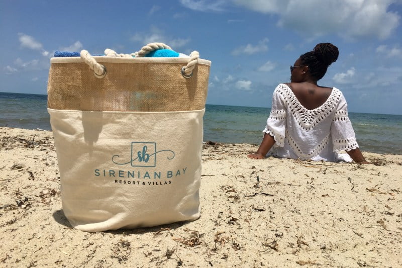 Meredith on the beach looking out to sea with her Sirenian Bay Resort and villas bag packed with beach gear