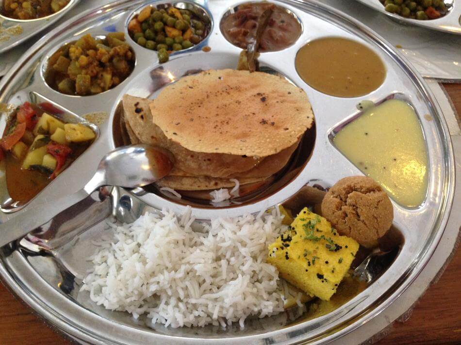 bread, rice, curries, vegetables and sauces on a metal platter