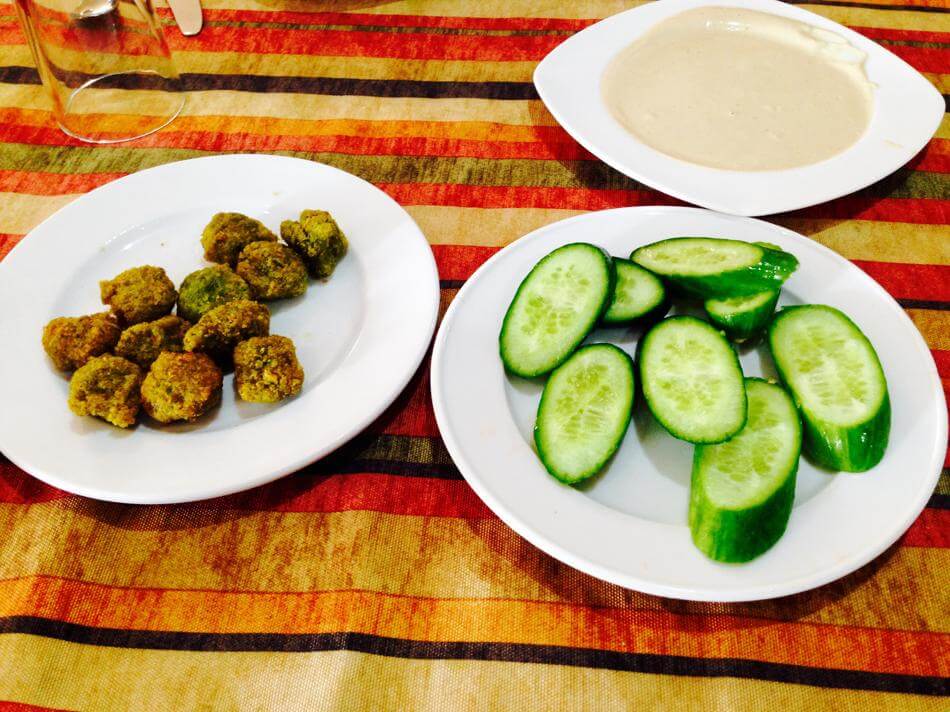 falafel tahini cucumber with sauce on 3 plates on red yellow toned tablecloth
