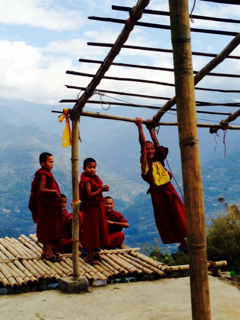 monk children playing on bamboo structure on top of mountain